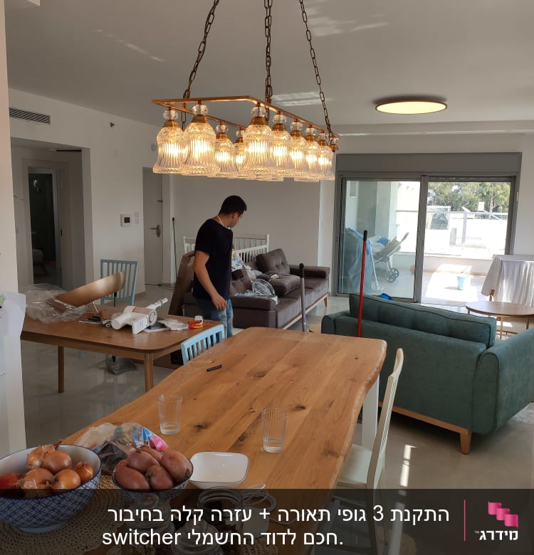 חשמלאי עובד על התקנת תאורה בתקרה